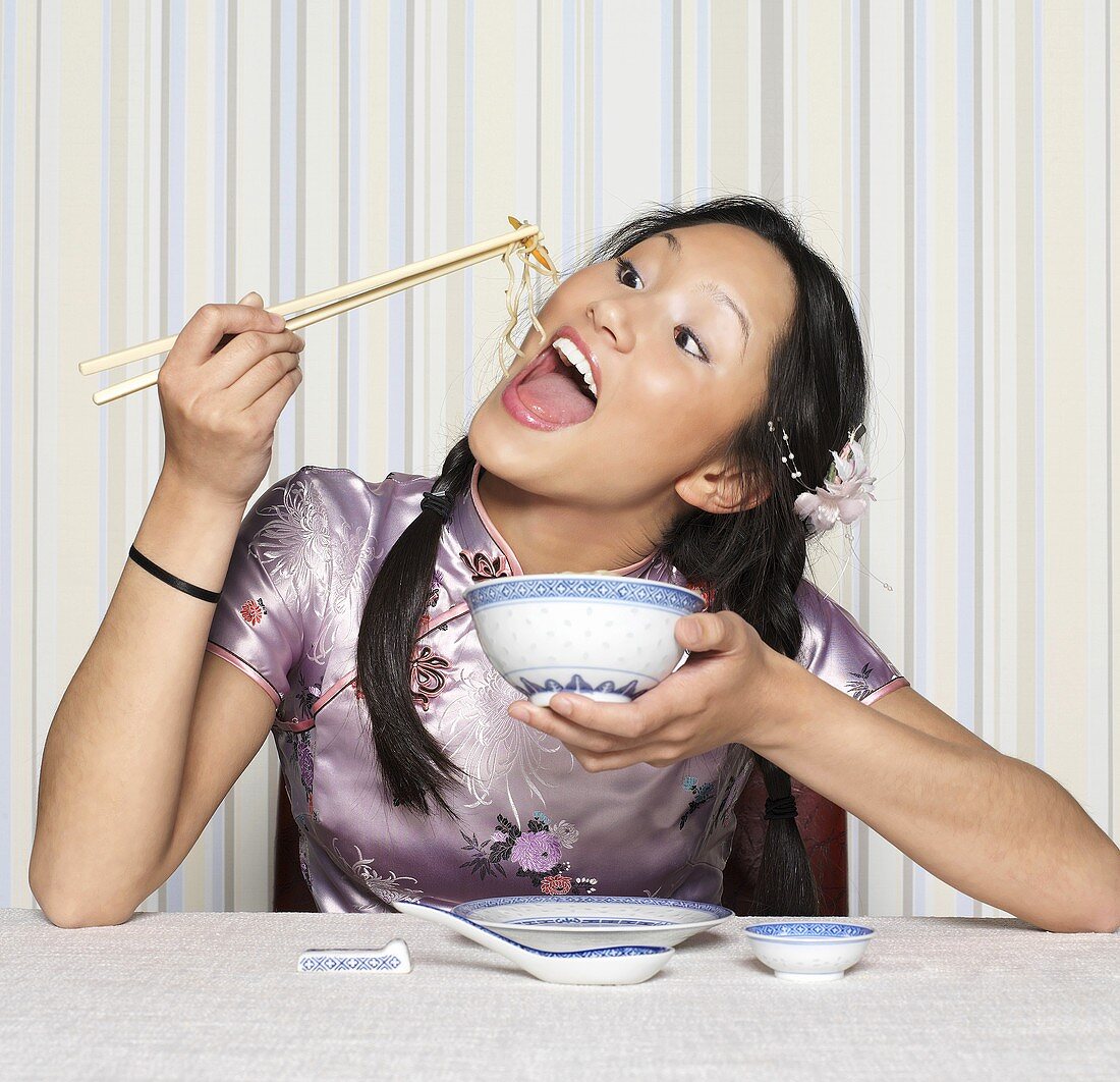 Asiatische Frau isst mit Essstäbchen