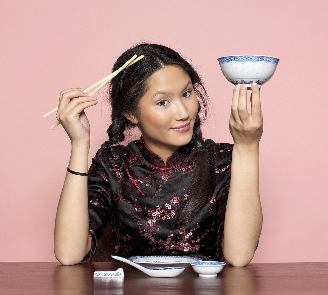 Asian woman holding chopsticks and bowl