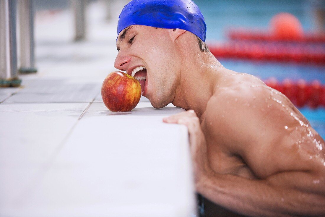 Schwimmer versucht mit dem Mund einen Apfel zu erreichen