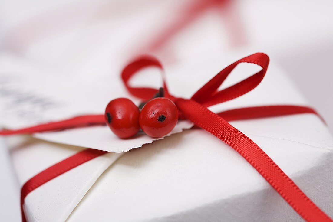 Päckchen mit rotem Geschenkband und Ilexbeeren