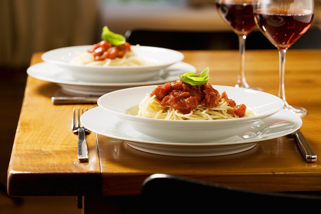 Two plates of spaghetti with tomato sauce