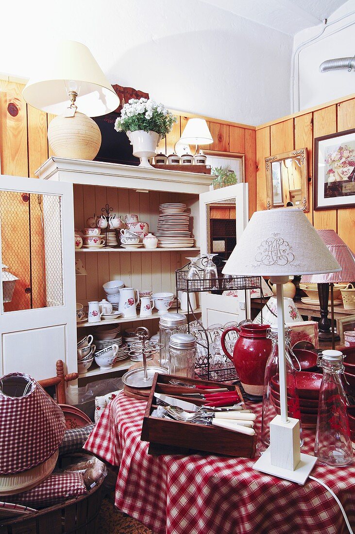 Crockery & cutlery on table, crockery cupboard in background