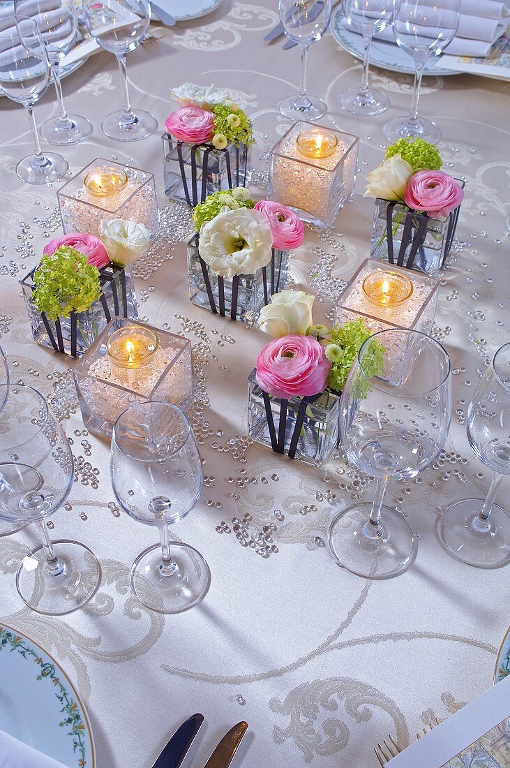 Table decoration of ranunculus, tealights and glass beads