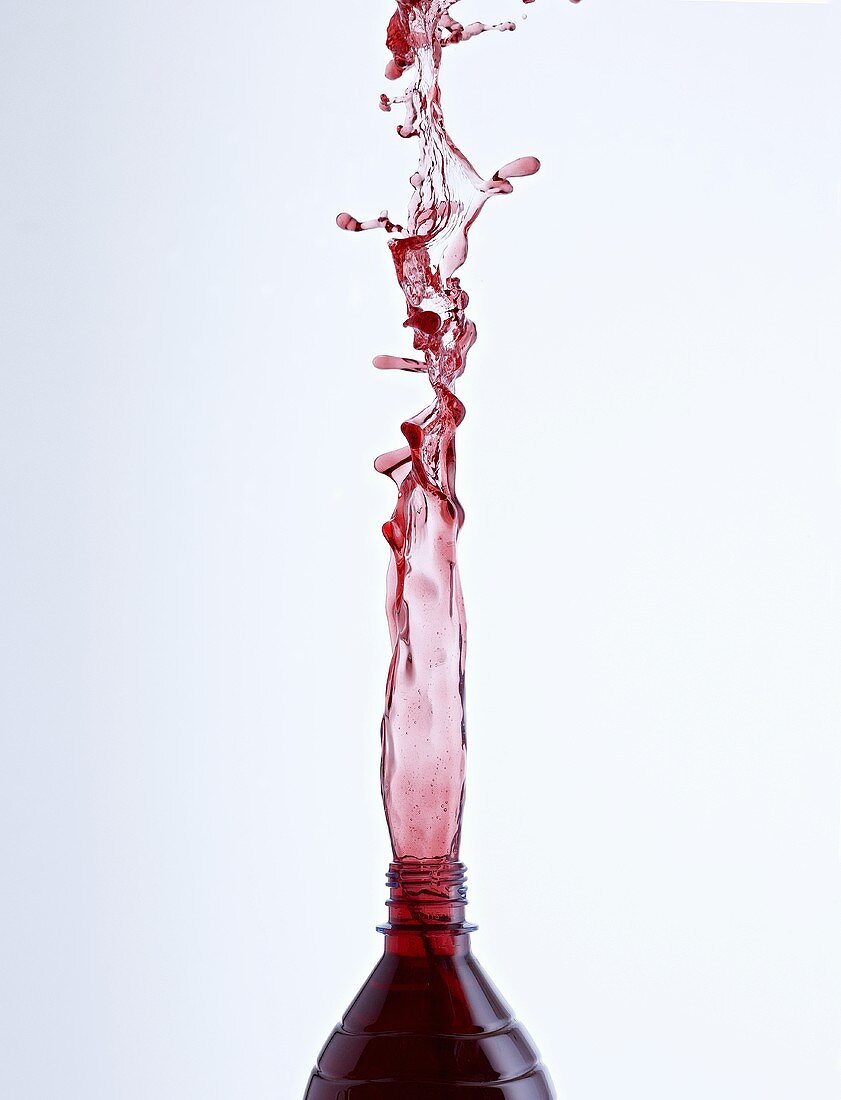 Cherry juice splashing out of a bottle
