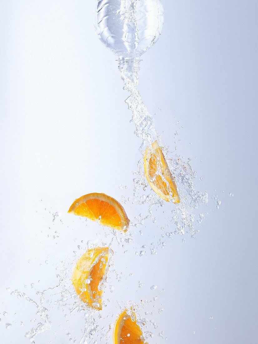 Wasser und Orangen aus Flasche schütten