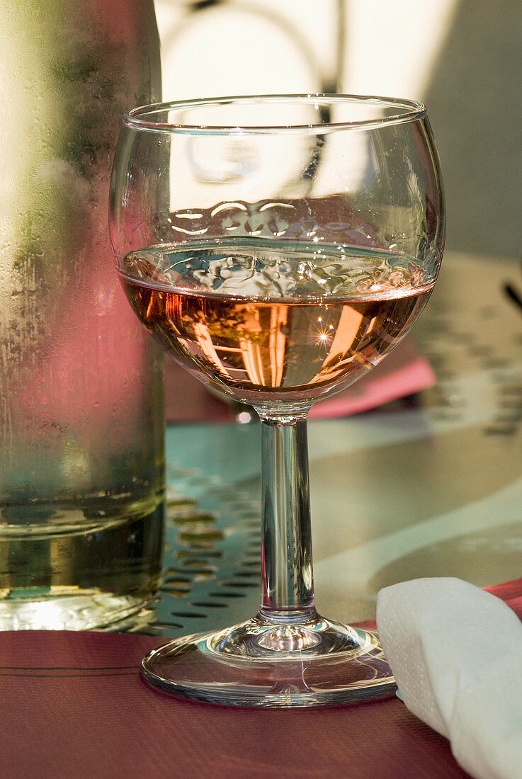 Glass of rosé wine beside wine bottle