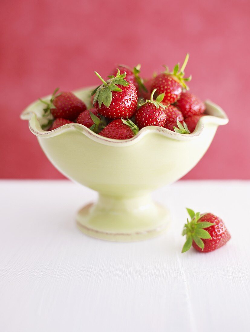 Fresh strawberries in and beside pedestal bowl