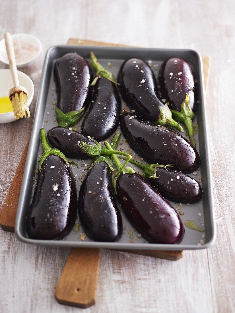 Seasoned aubergine halves on baking tray
