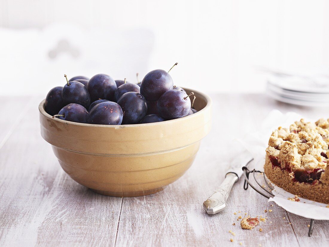 Fresh plums in bowl, plum cake beside it