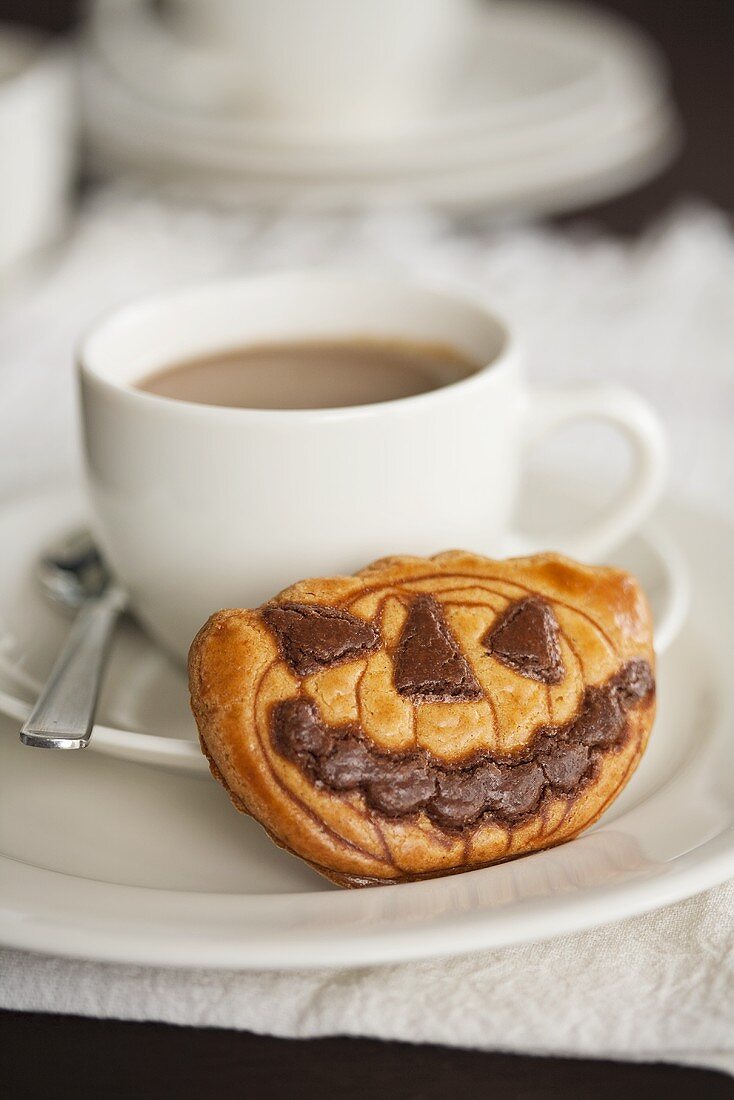 A cup of coffee with a pumpkin biscuit for Halloween