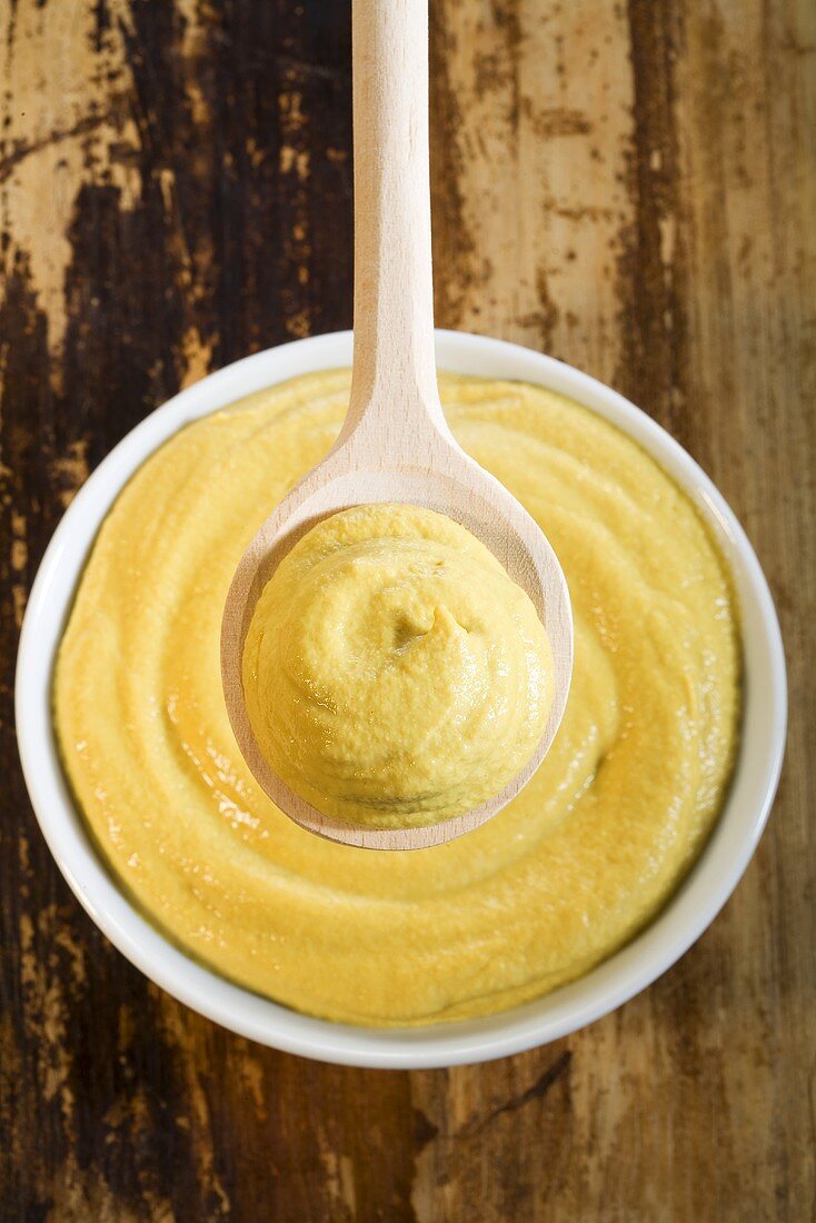 Mustard on wooden spoon and in small dish