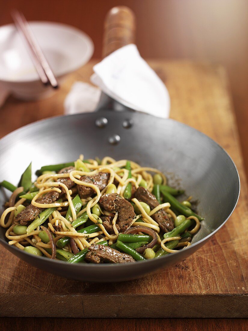 Noodles with beef and green beans in wok