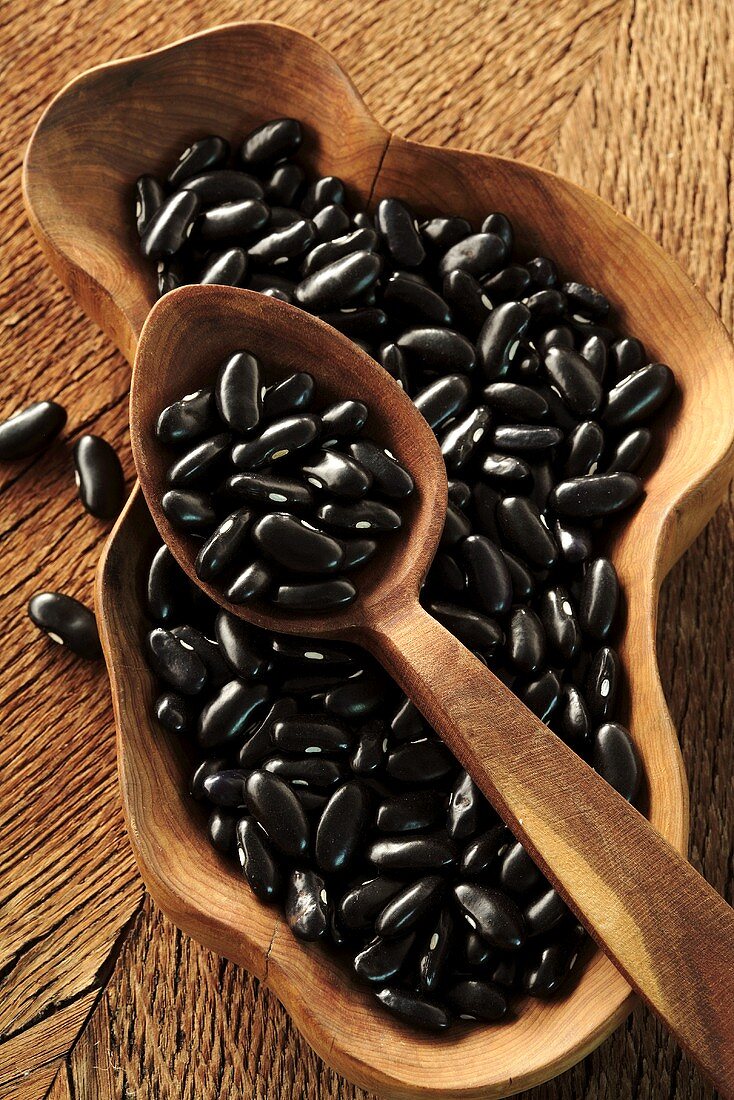 Black beans in wooden dish and on wooden spoon