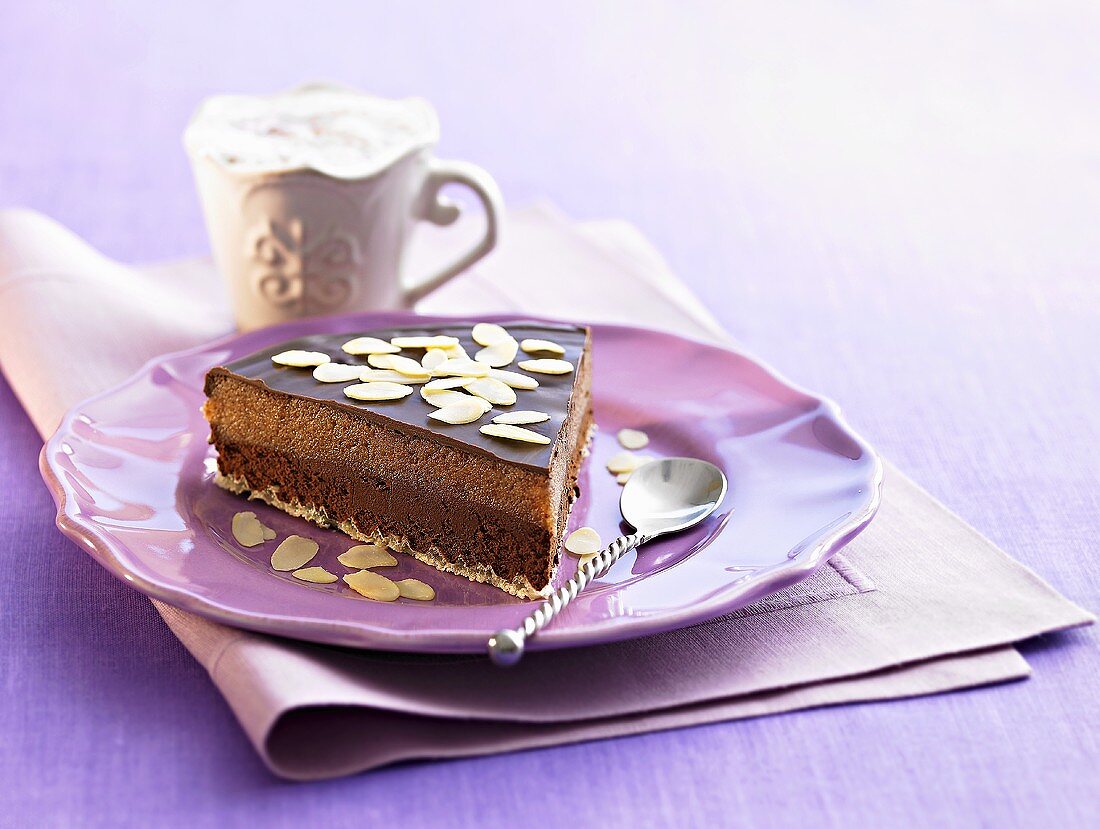 Piece of chocolate cake with flaked almonds, cappuccino
