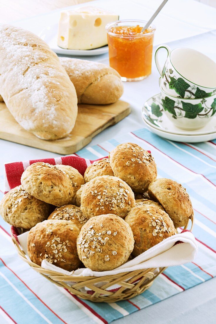 Wholemeal rolls in bread basket, bread, marmalade and cheese