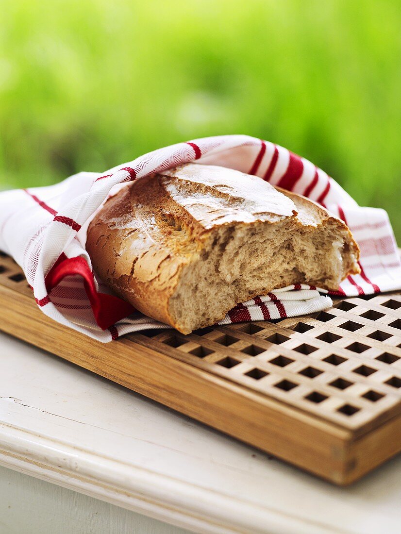 Broken bread in tea towel on breadboard