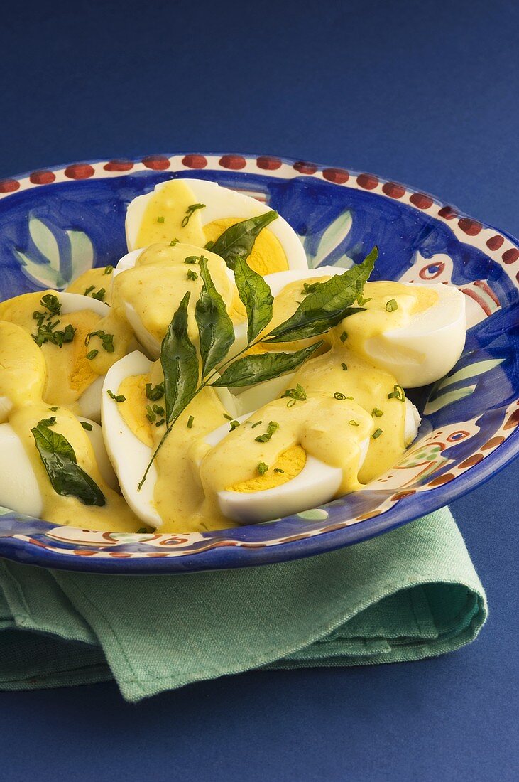Boiled eggs with curry sauce and herbs
