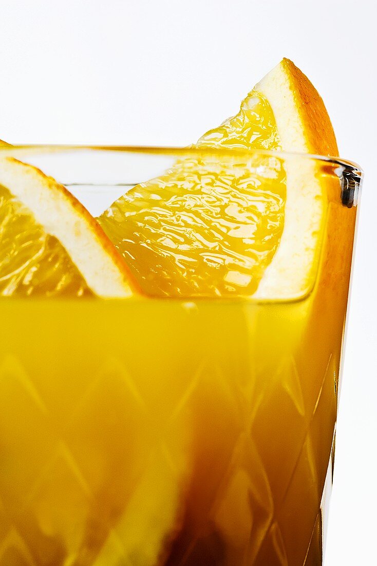 Orange juice with orange slices in glass (close-up)