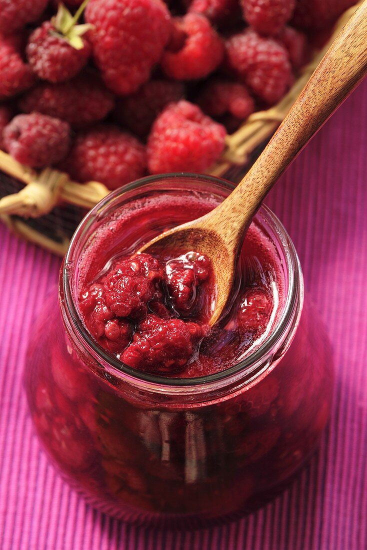 Raspberry jam in jar with wooden spoon