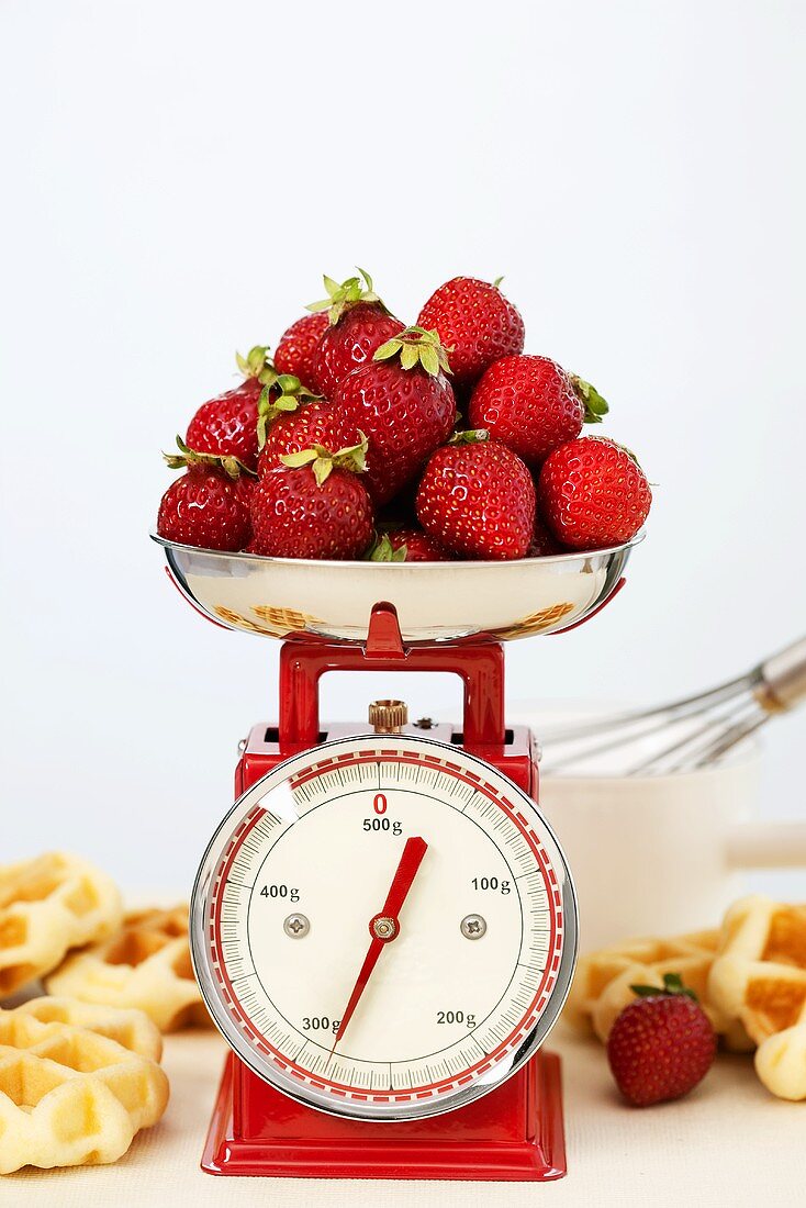 Strawberries on kitchen scales, waffles beside them