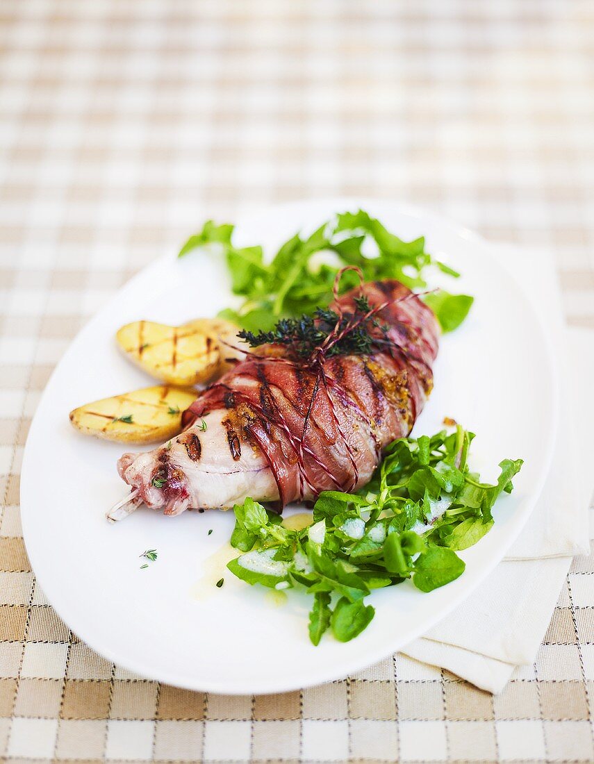 Bacon-wrapped rabbit leg with wild herb salad