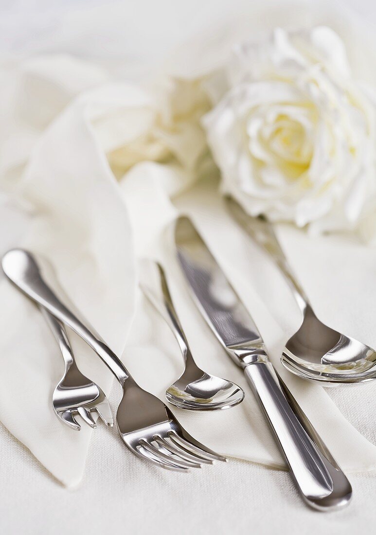 Cutlery on napkins with white rose