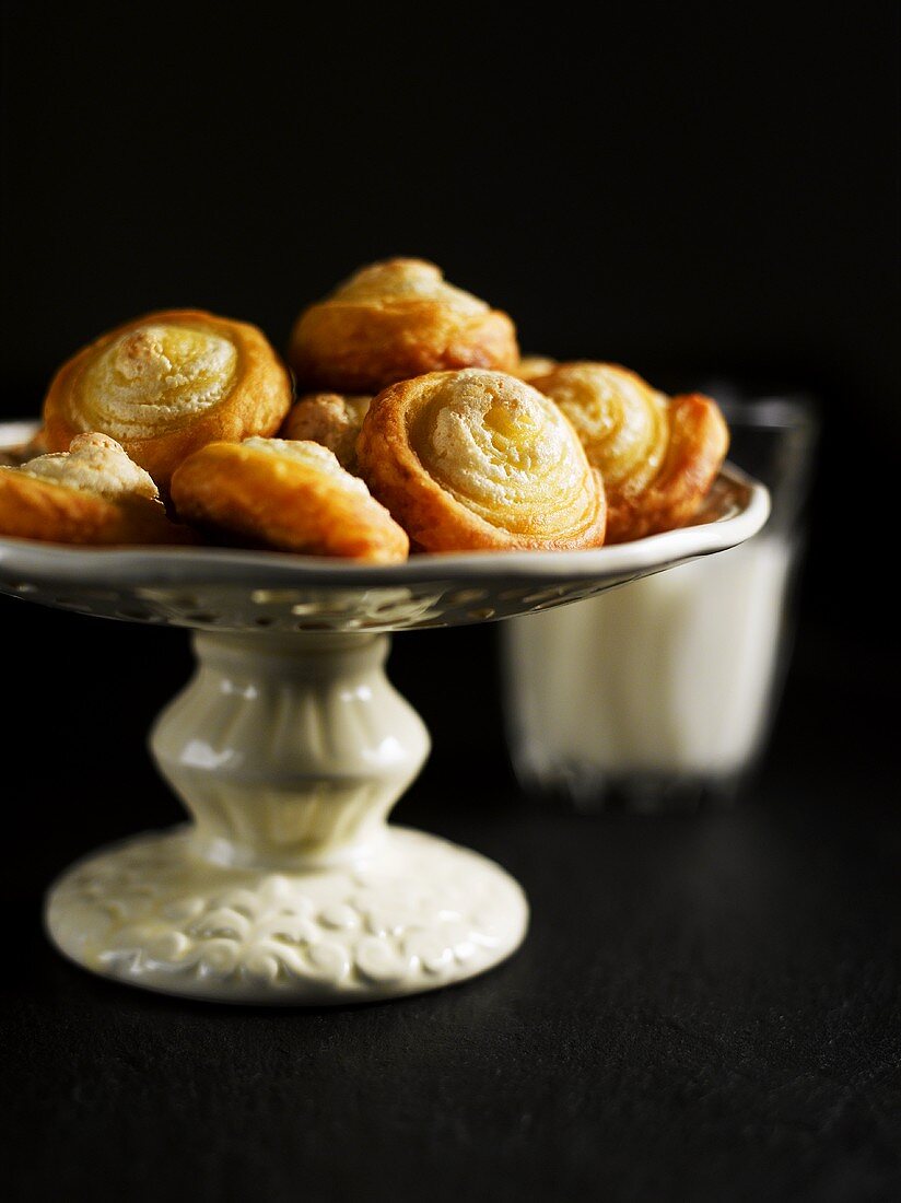 Quark pastry pinwheels with meringue on cake stand, glass of milk