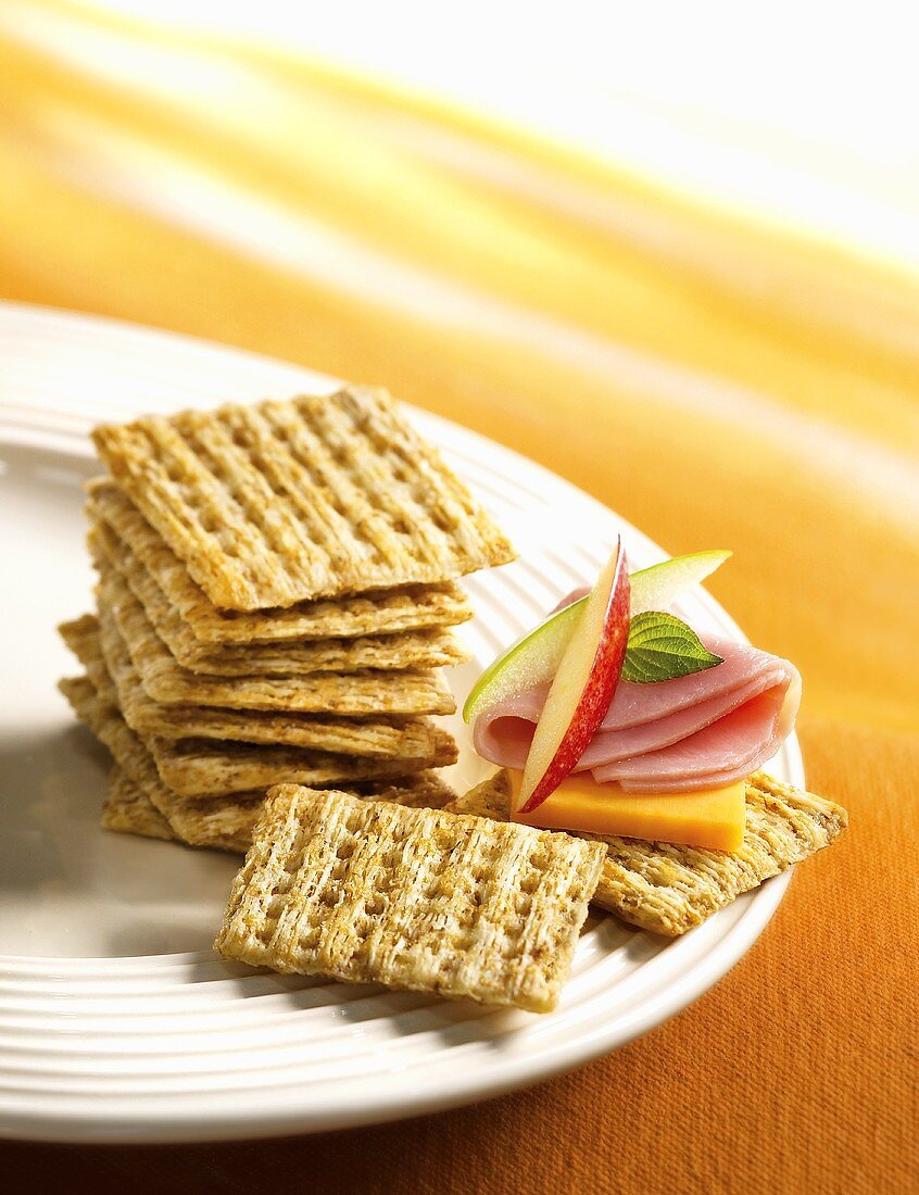 Crackers, one topped with cheese and ham