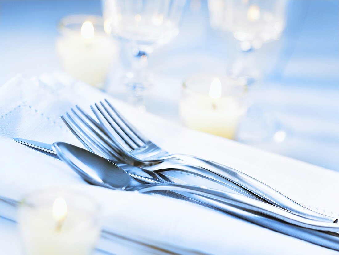 Cutlery on napkin, candles in glasses
