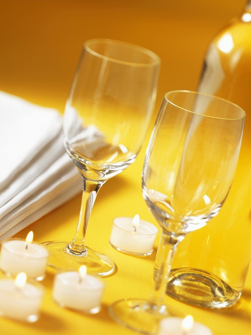 Wine glasses and tealights on yellow background