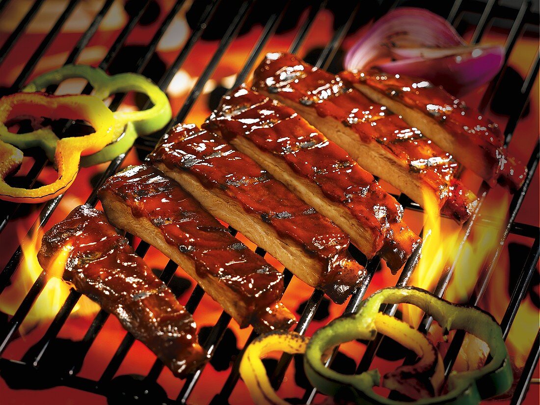 Spare ribs and slices of pepper on a barbecue