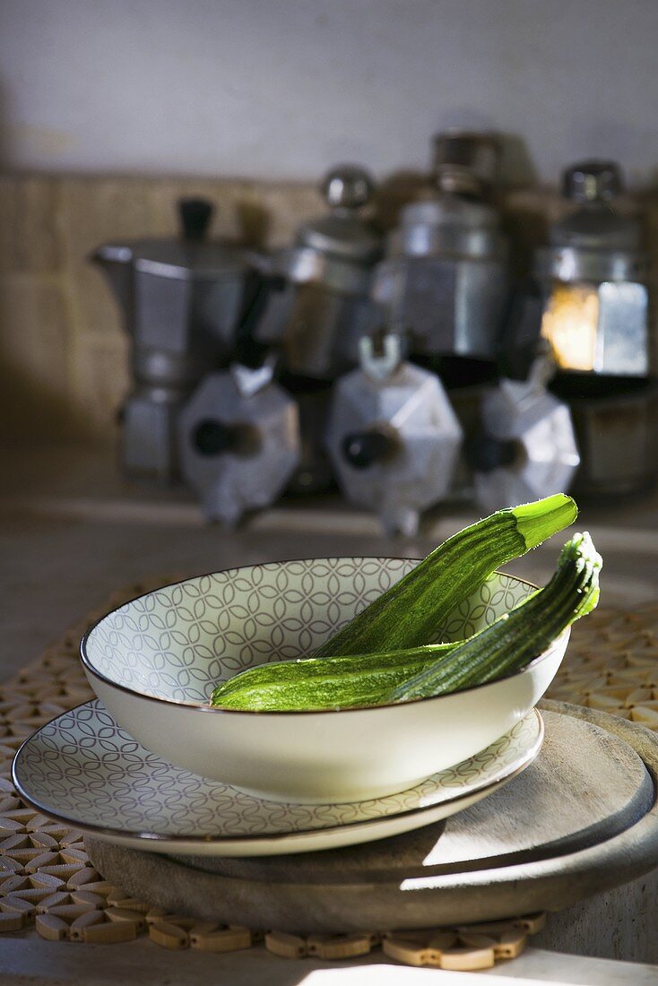 Courgettes in dish in front of old espresso makers