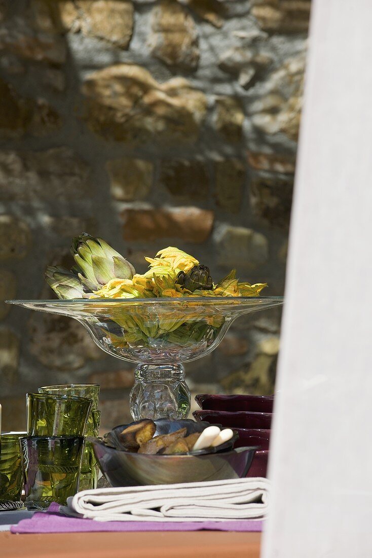 Tischdeko mit Artischocken und Zucchiniblüten (Italien)