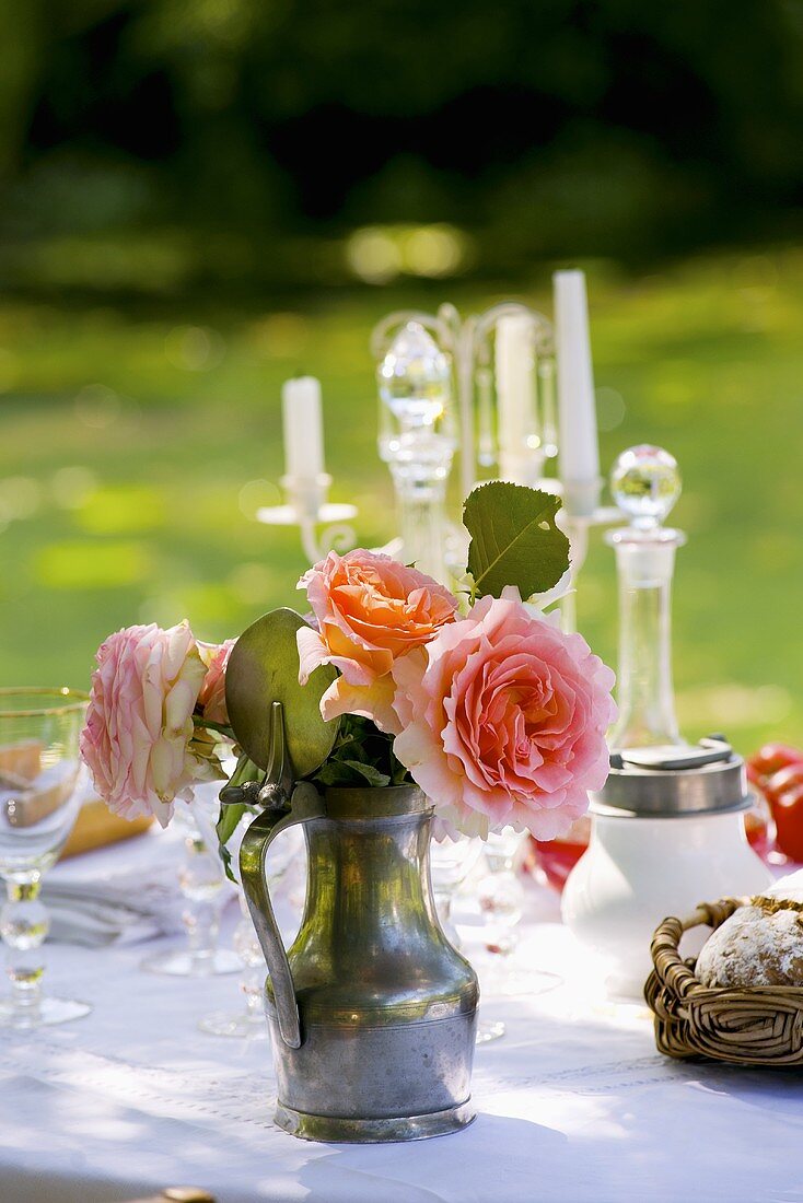 Jug of roses on laid table in garden