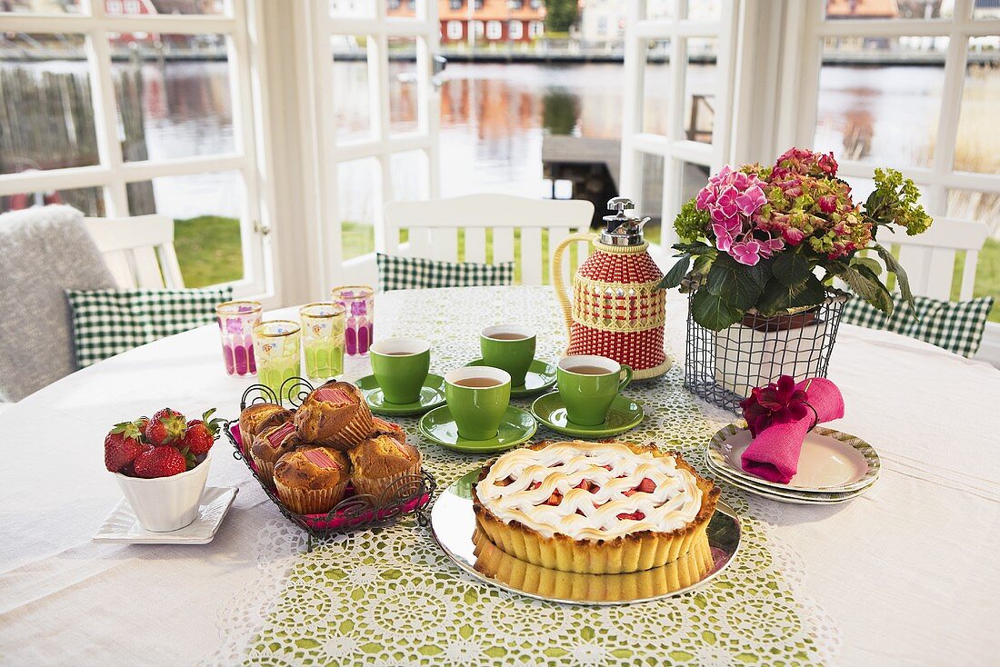 Rhubarb pie, rhubarb muffins and tea on springtime table