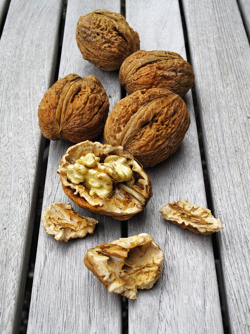 Walnuts, whole and cracked open, on wooden table