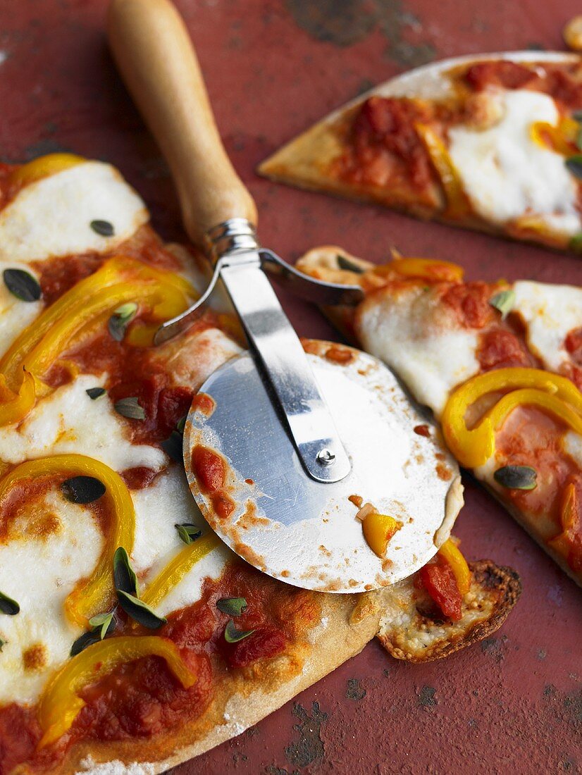 Pizza Margherita mit Pizzaschneider zerteilen