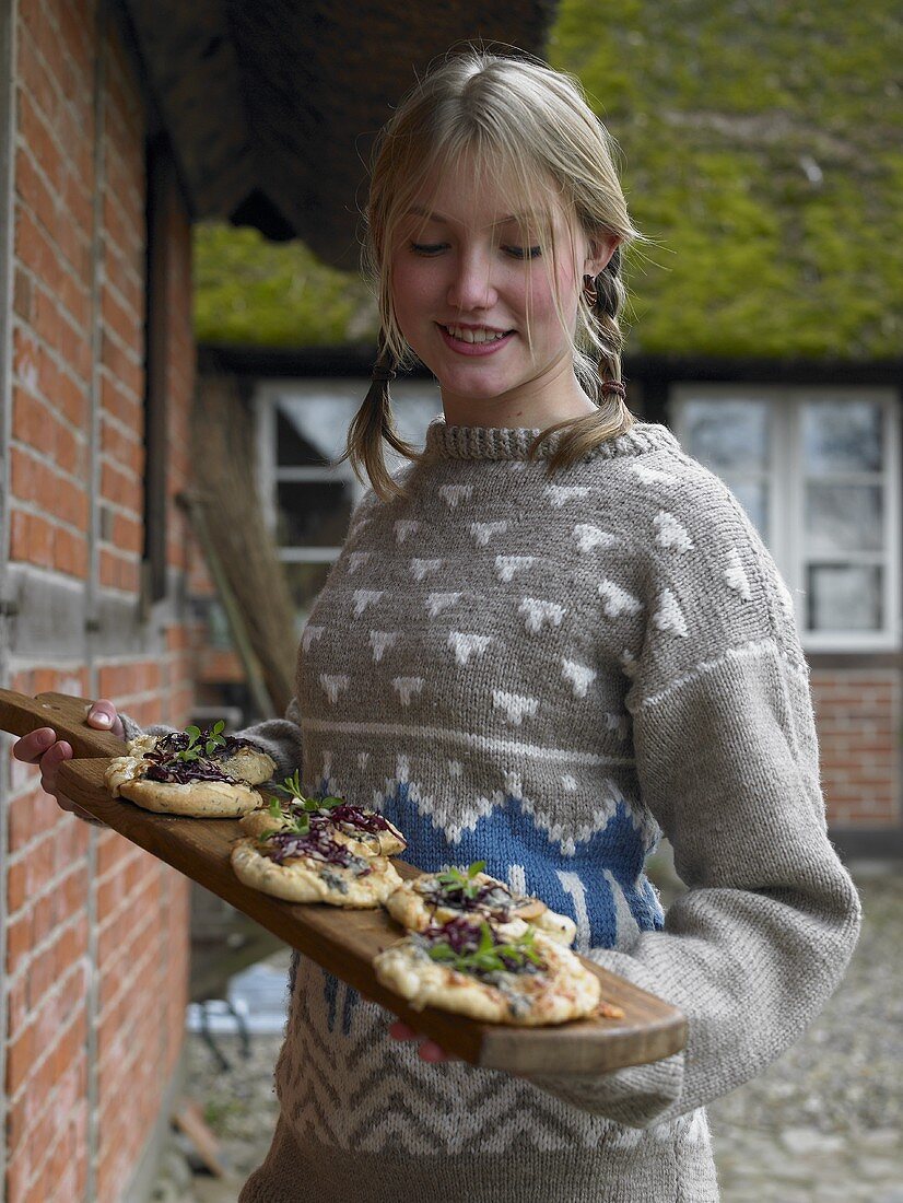 Young woman serving pizzette on wooden tray