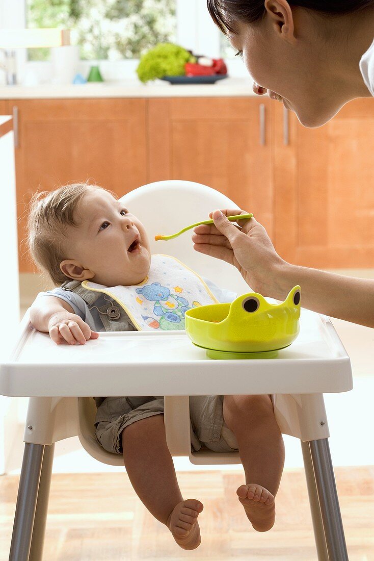 Mother feeding her baby with baby food