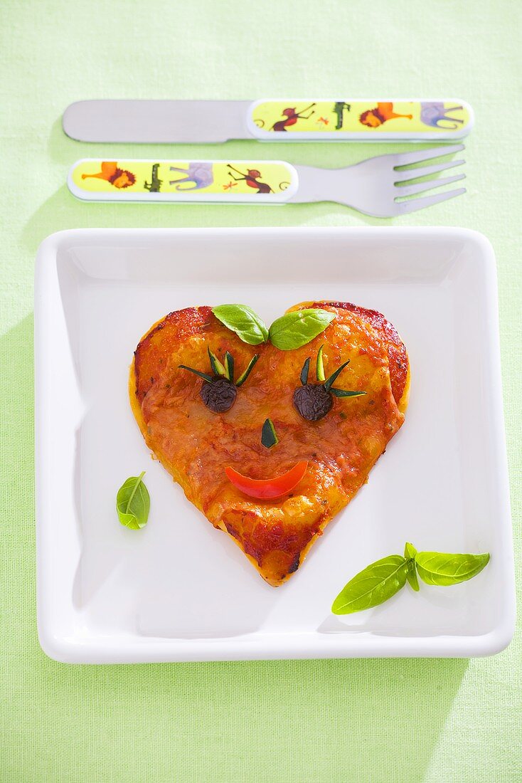 Heart-shaped pizza with amusing face for a child