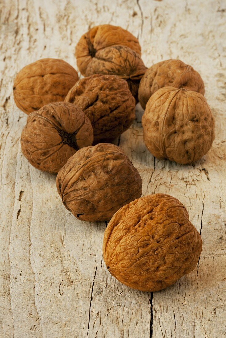 Several unshelled walnuts on wooden background