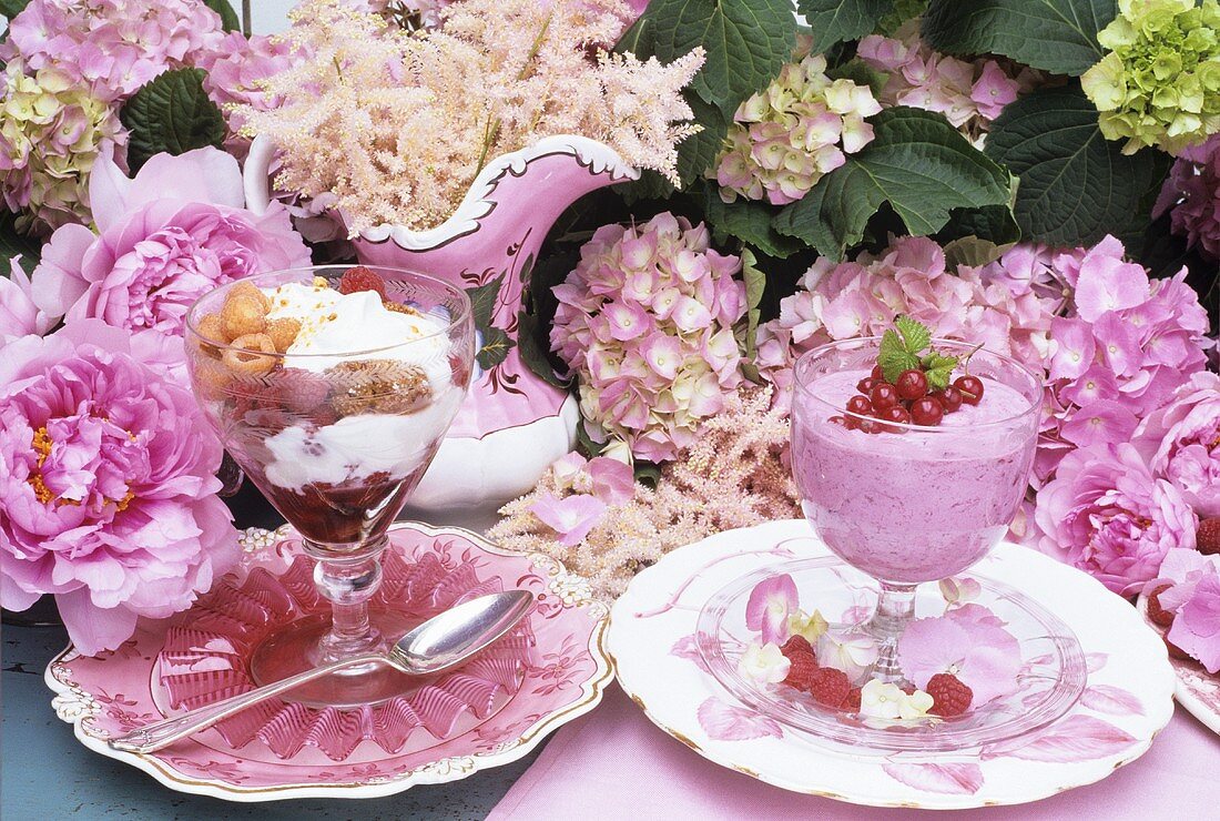 Desserts mit Beeren auf Tisch mit rosa Blumen