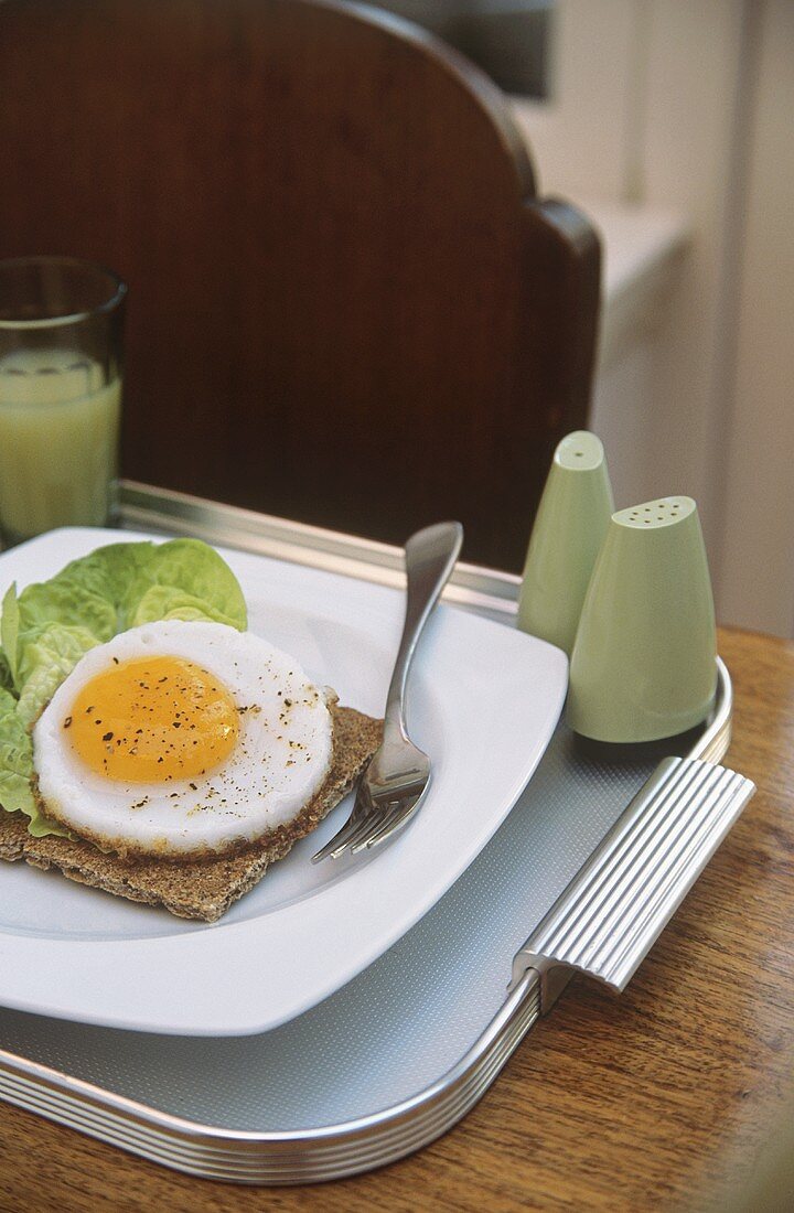 Crispbread with fried egg and lettuce leaf for breakfast