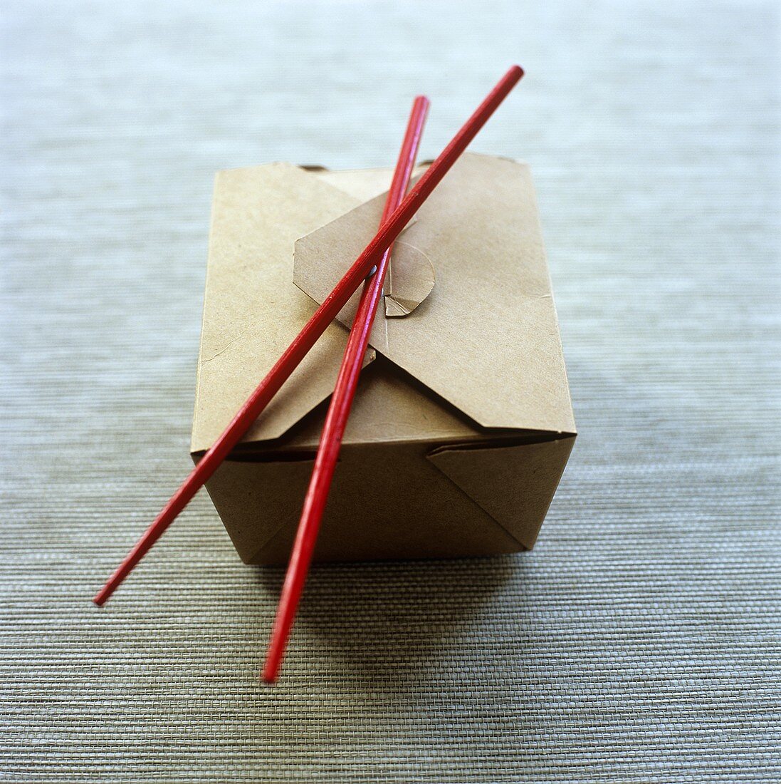 A noodle box with chopsticks