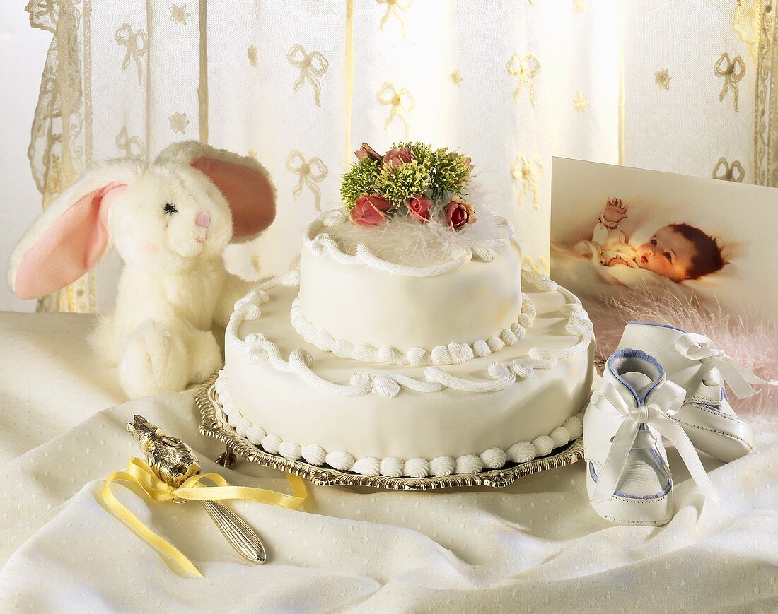 Two-tiered white cake with gifts for christening