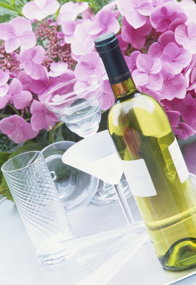 A bottle of white wine with hydrangeas in background