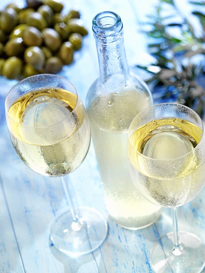 White retsina in glasses and bottle, olives behind