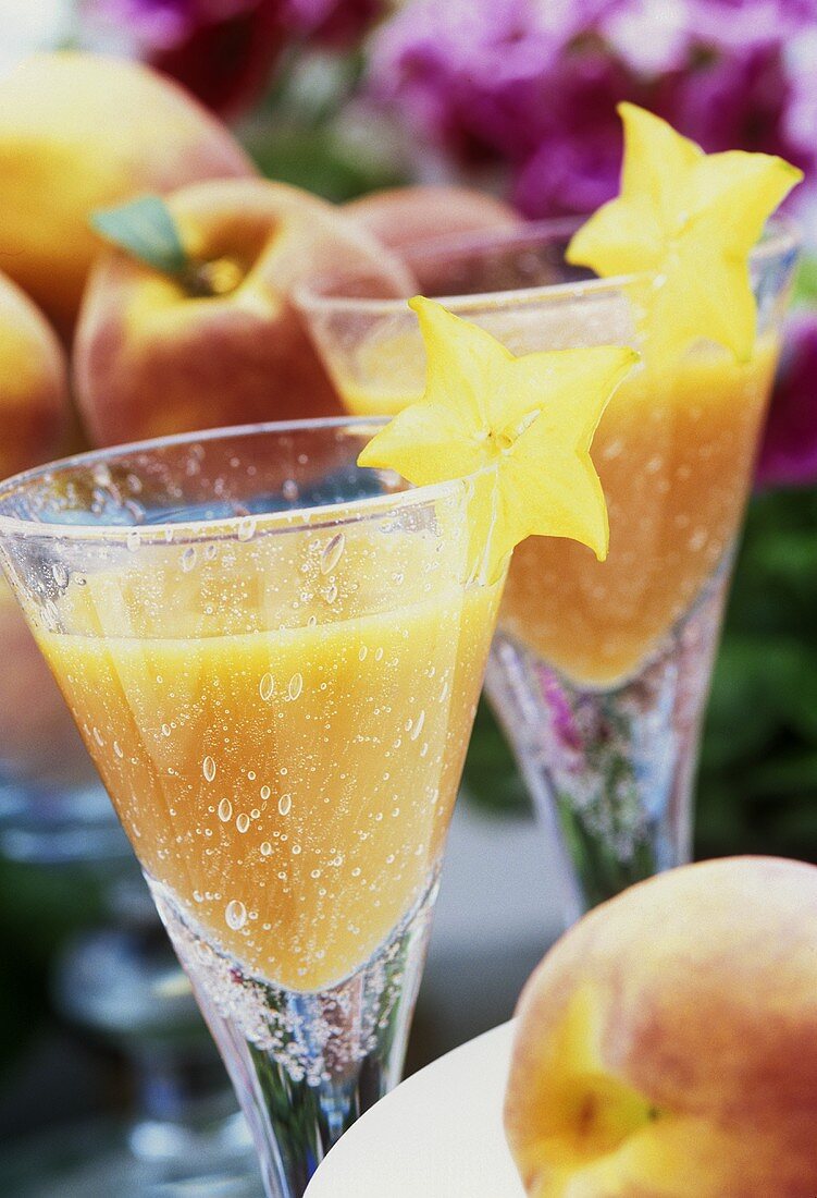 Two glasses of peach cocktail with carambola slices