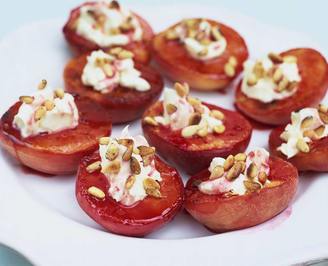 Baked peaches with raspberry sauce, cream and pine nuts