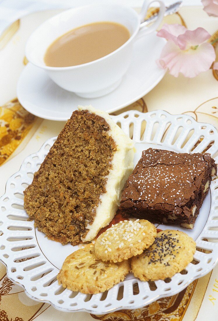 Teller mit Kuchen & Gebäck vor Tasse Tee mit Milch